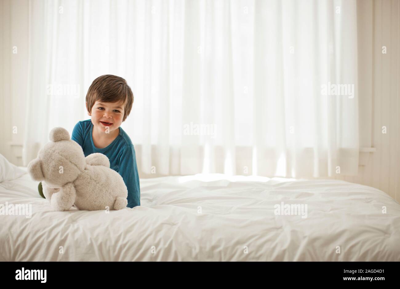 Junge Junge spielt auf einem Bett in einem Schlafzimmer. Stockfoto