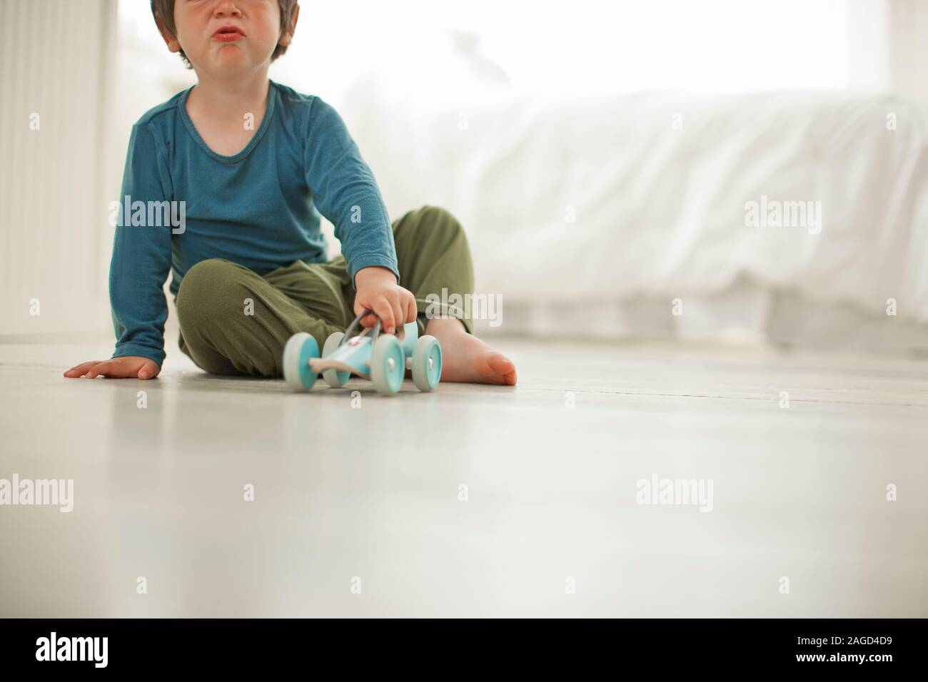 Junge Junge spielt mit einem spielzeugauto in seinem Schlafzimmer. Stockfoto