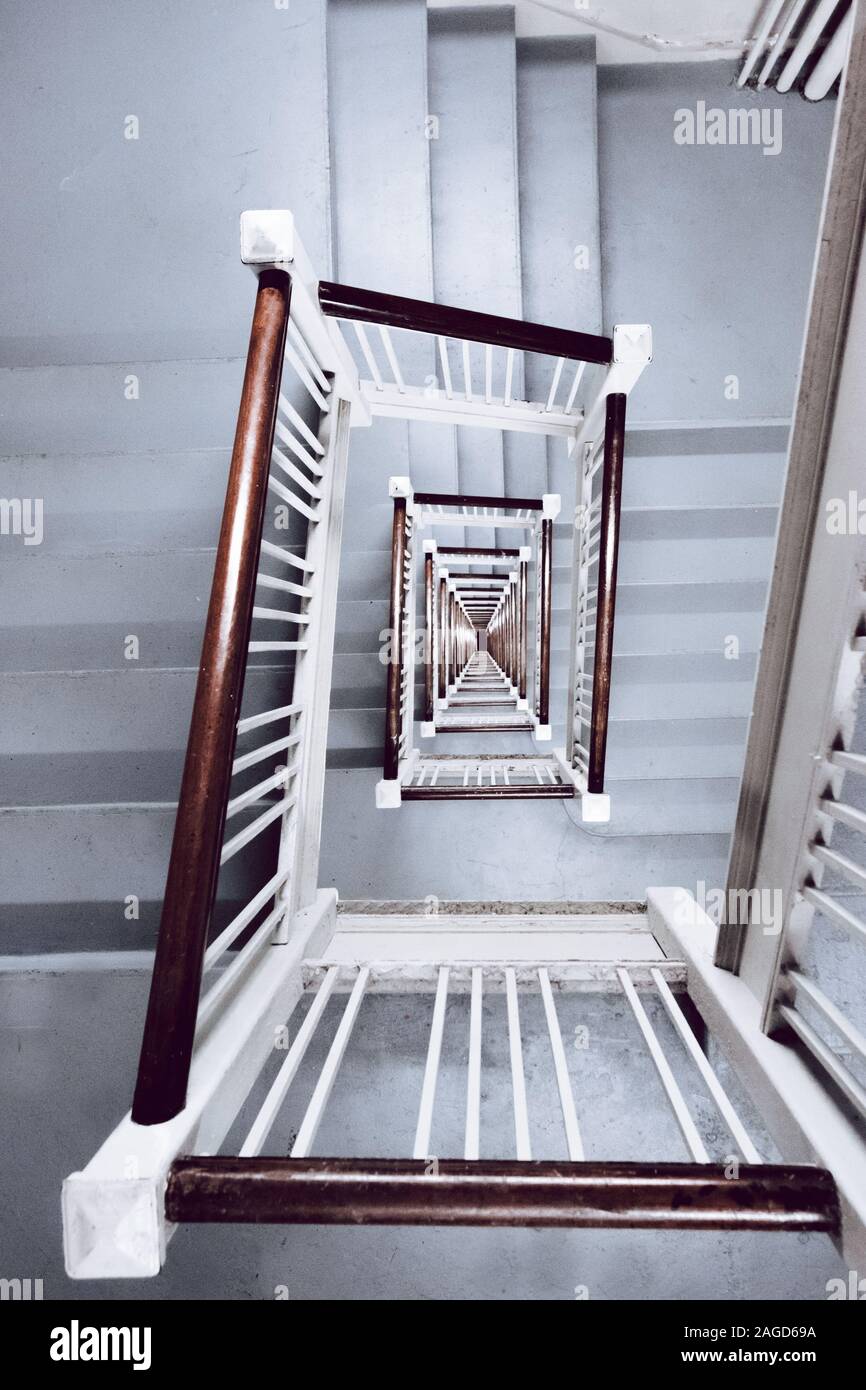 Vertikale Hochwinkelaufnahme einer weißen Treppe mit Holz Handläufe Stockfoto