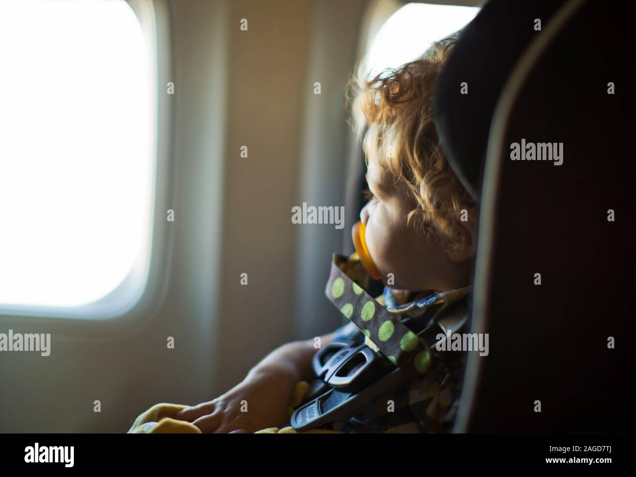 Junge in einem Autositz sitzen in einem Flugzeug. Stockfoto
