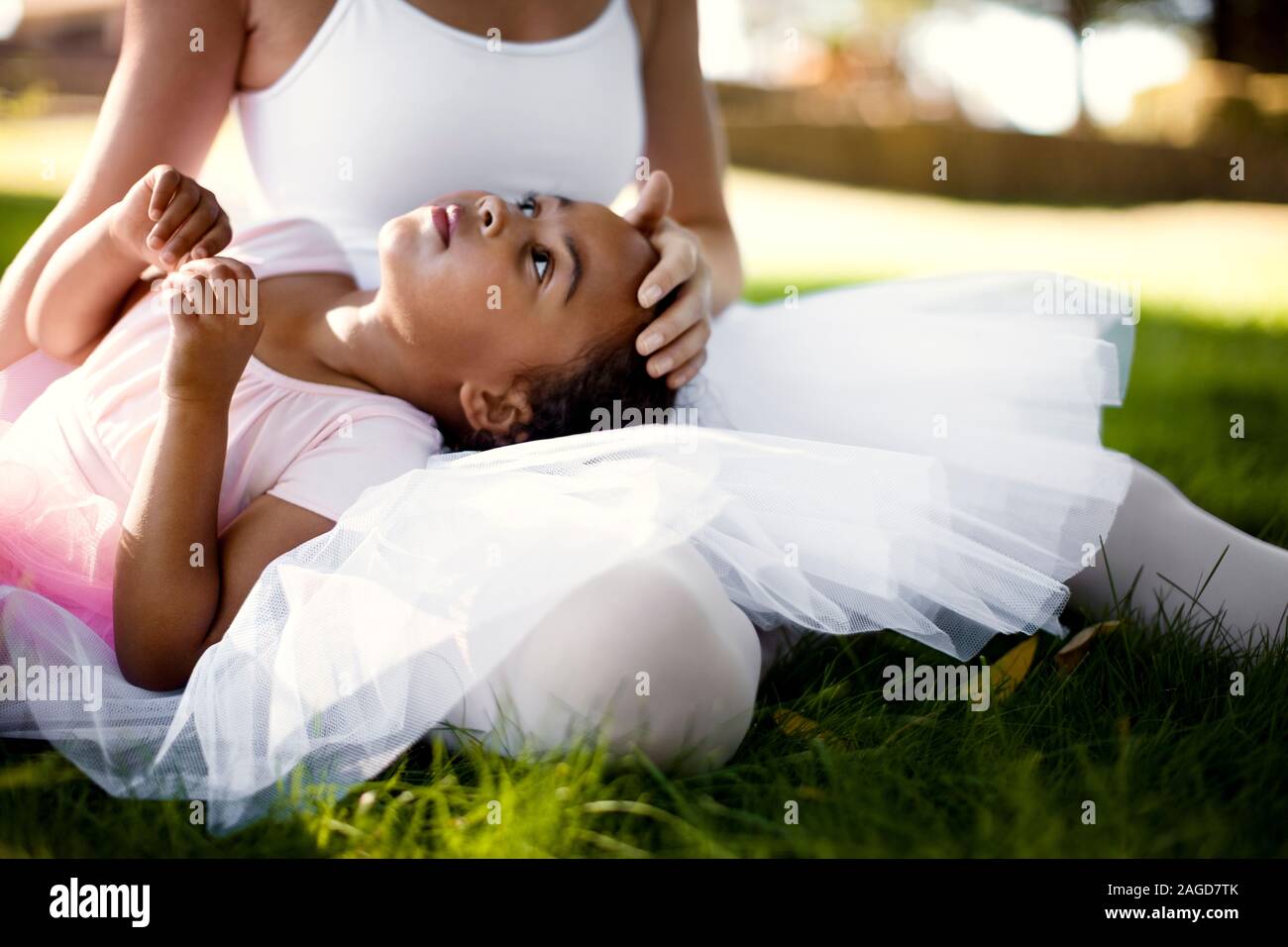 Junges Mädchen und ihre Mutter tragen Ballett Bekleidung Entspannung auf einem Rasen Stockfoto