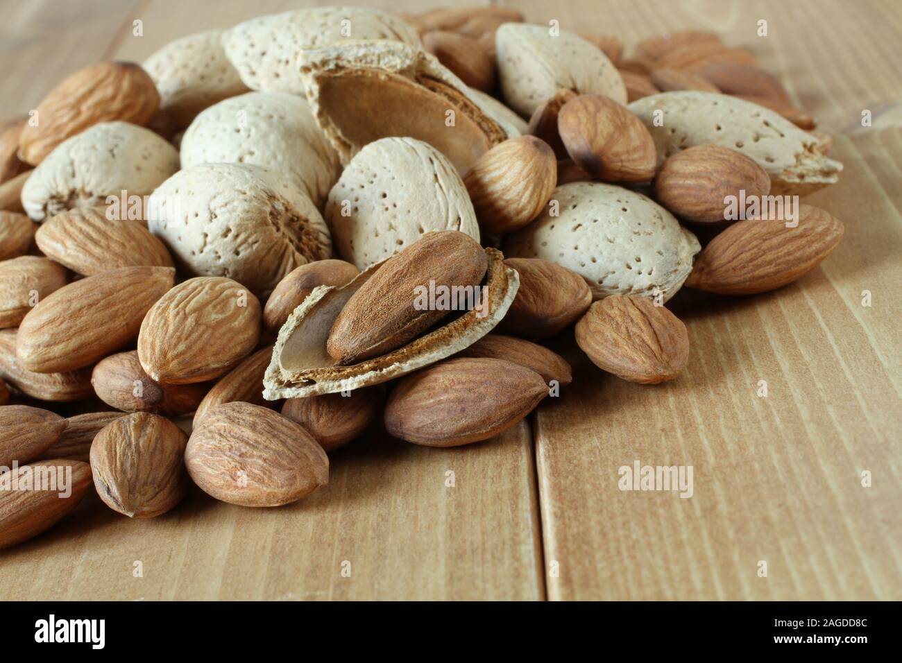 Stapel der geschälte rohe Mandeln und rohen Mandeln mit Muscheln auf Holztisch. Nahaufnahme Stockfoto