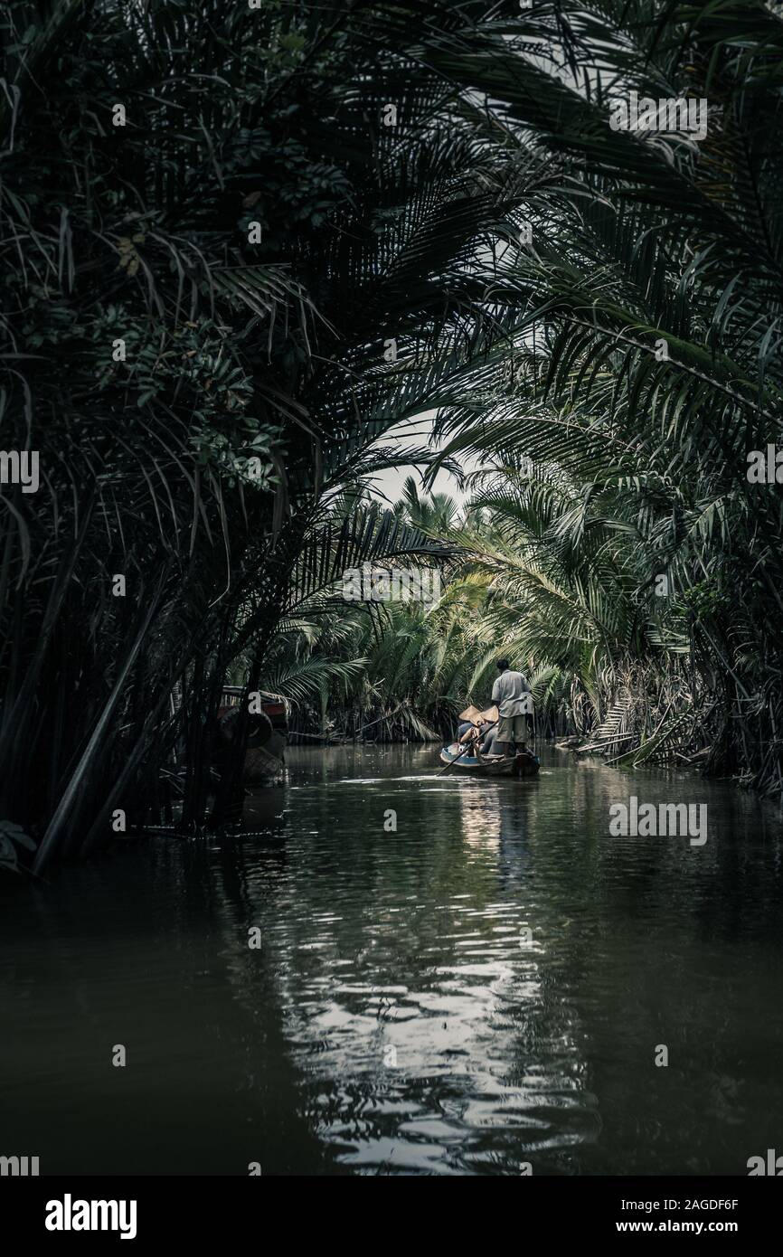 Vertikale Aufnahme von Menschen in einem Boot in der Mitte Des Sees mit dem Spiegelbild von Palmen Stockfoto