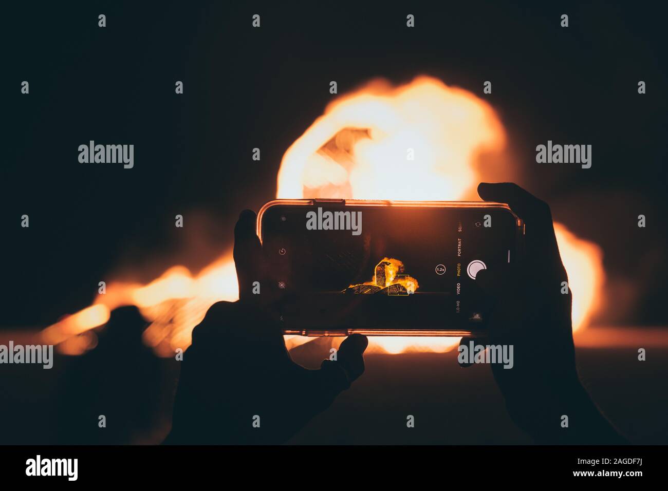 Person, die mit einem Smartphone ein Bild vom Lagerfeuer gemacht hat Nachts Stockfoto