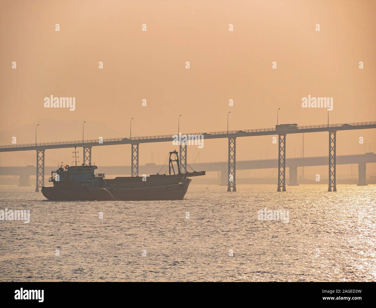 Sonnenuntergang auf dem Frachtschiff und alten Macau Taipa Brücke in Macau, China Stockfoto