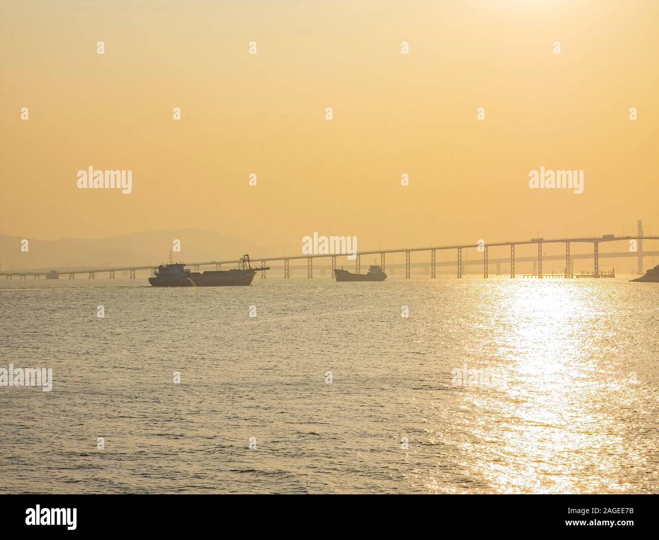 Sonnenuntergang auf dem Frachtschiff und alten Macau Taipa Brücke in Macau, China Stockfoto