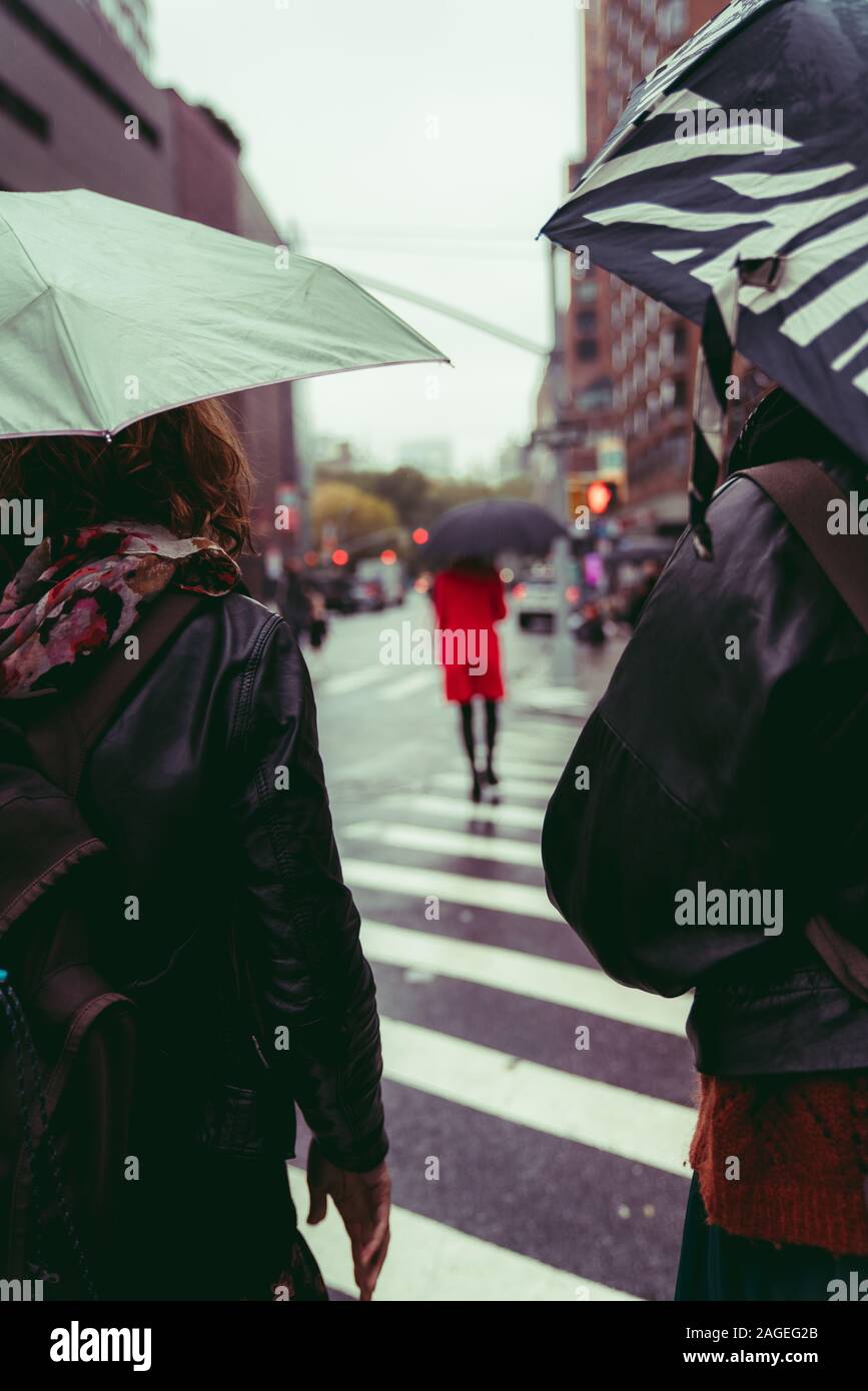 Vertikale Aufnahme einer Gruppe von Menschen, die auf dem laufen Straße unter dem Regen Stockfoto