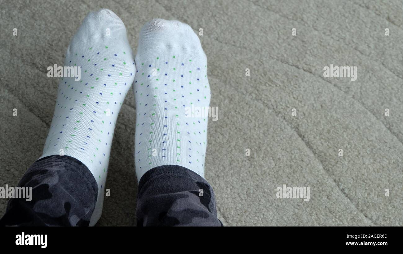 Beine mit ein Paar lange Hosen und weißen gepunktete Socken, auf einen Teppich zu stellen. Stockfoto