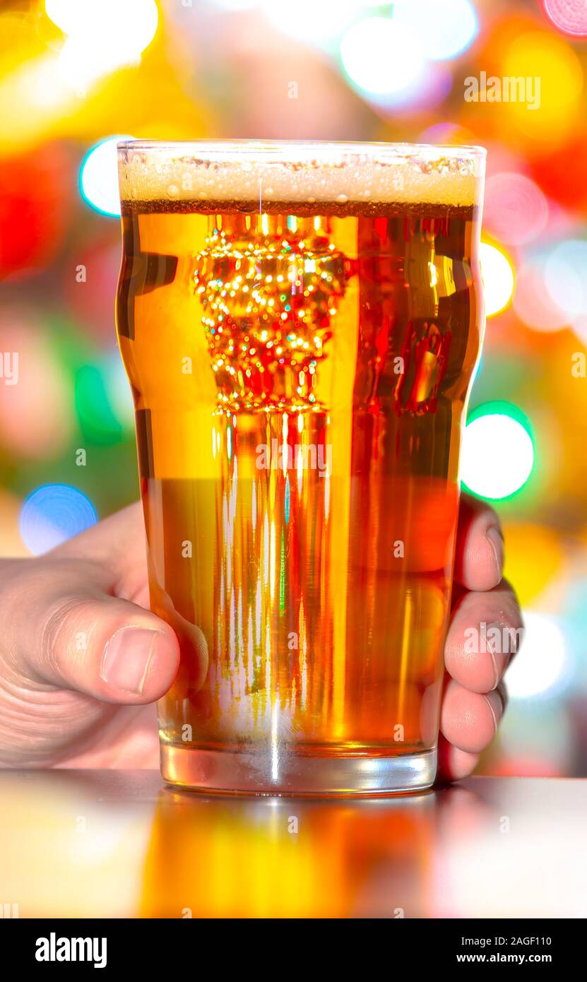 Ein Pint Bier und Glas mit Weihnachtsbeleuchtung auf dem Hintergrund Stockfoto