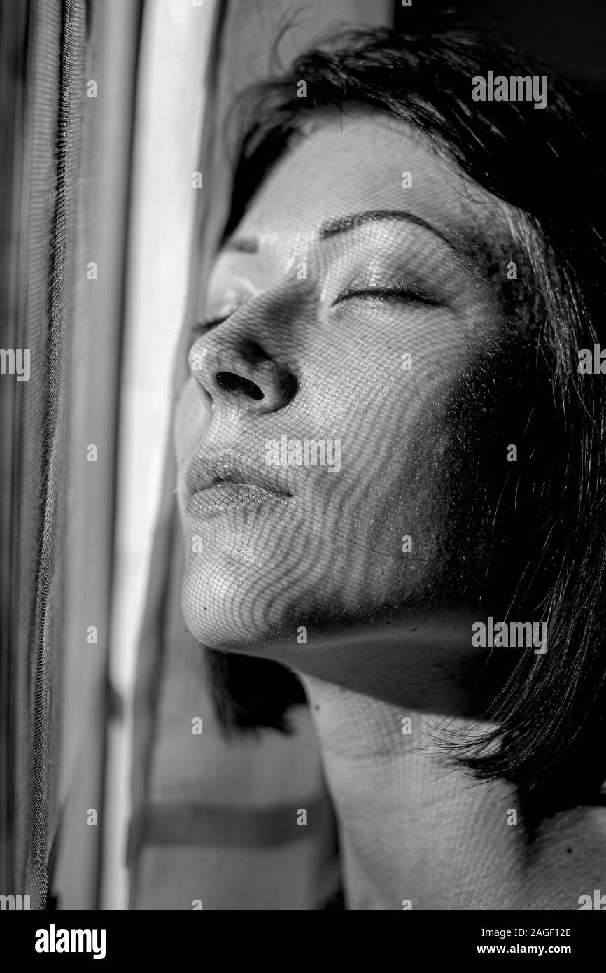 Porträt der Frau, die in der Nähe der Fenster im Schatten Stockfoto