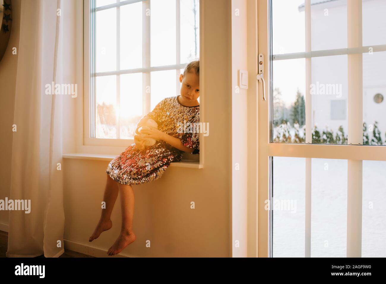 Junge Mädchen traurig saß auf dem Fensterbrett zu Hause bei Sonnenuntergang Stockfoto