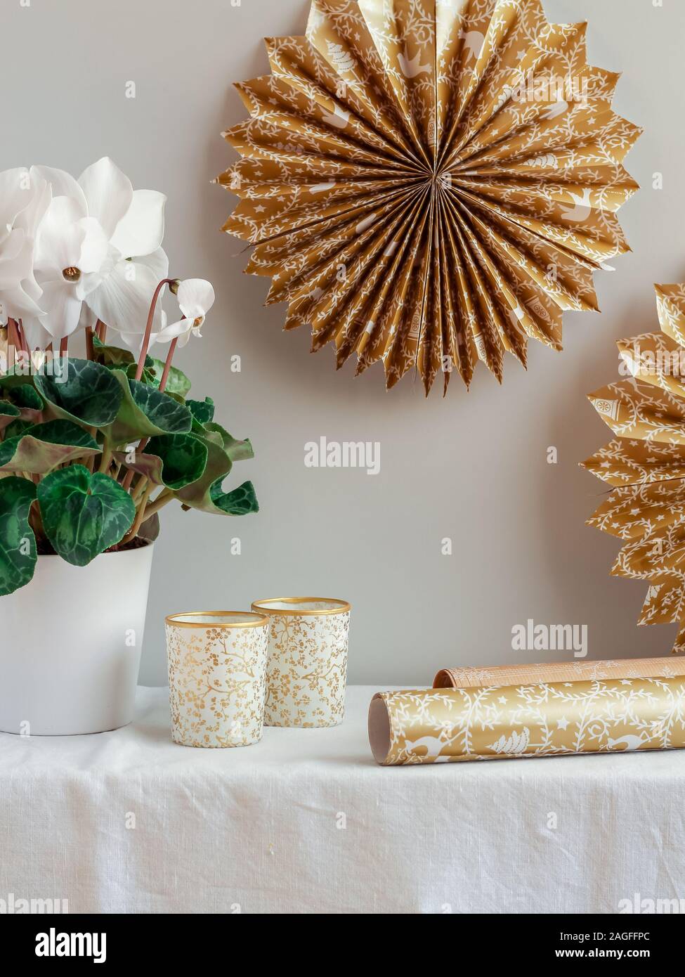 Handgefertigte goldene Papiersterne und Kerzen mit Cyclamenblume zur Dekoration eines Wohnzimmers Stockfoto