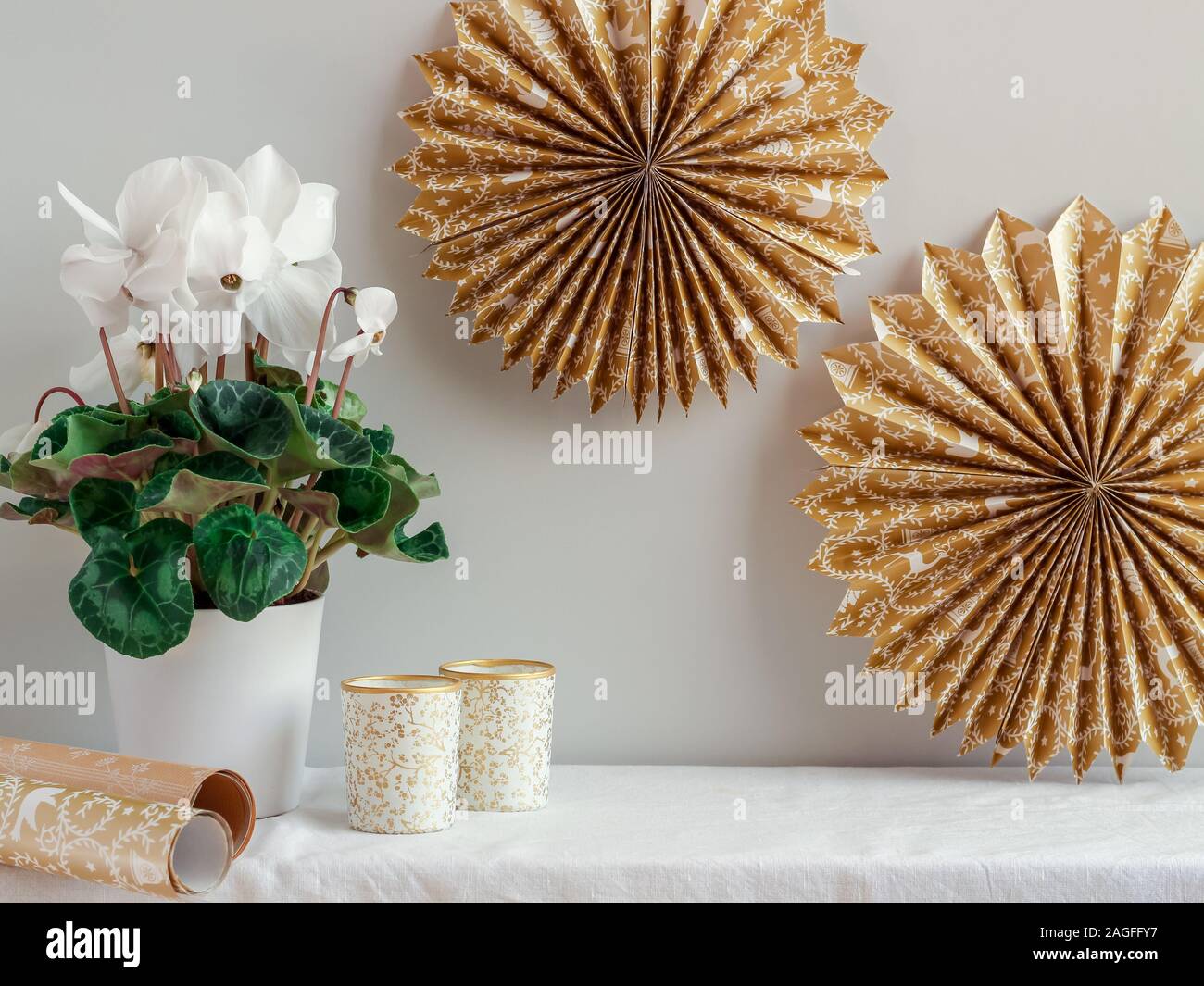 Handgefertigte goldene Papiersterne und Kerzen mit Cyclamenblume zur Dekoration eines Wohnzimmers Stockfoto