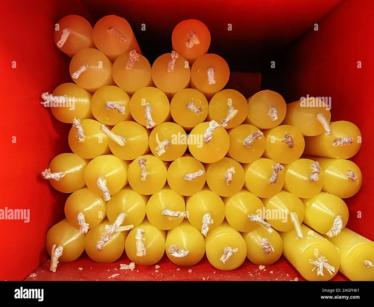 Gruppe von gelben Kerzen mit weißen Dochte in ein rotes Quadrat. Nahaufnahmen mit wenig Tageslicht. Stockfoto