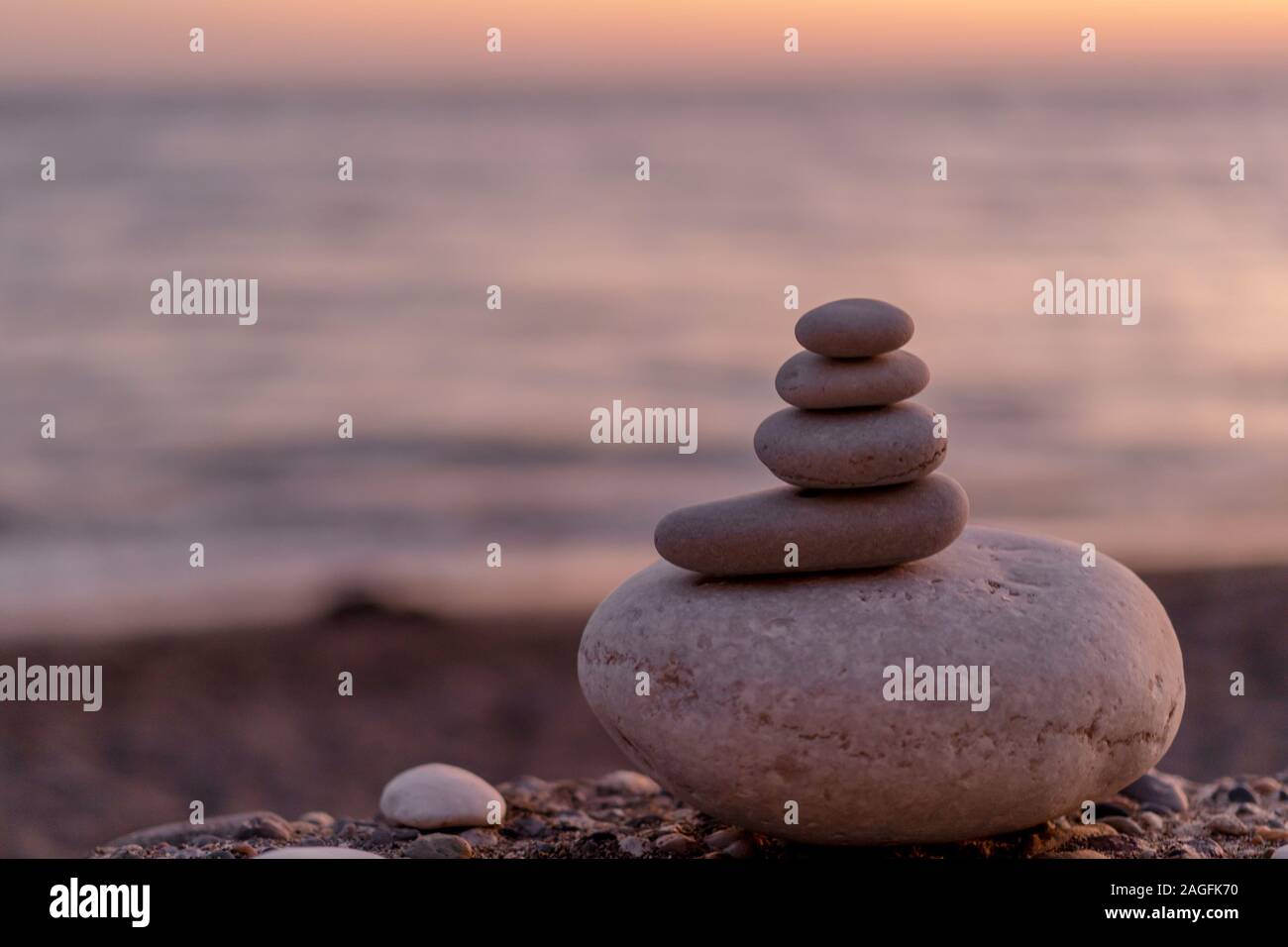 Perfekte Balance von Stapel von Pebbles am Meer in Richtung Sonnenuntergang. Konzept der Balance, Harmonie und Meditation. Helfende oder unterstützende jemand für wachsende oder höher. Stockfoto
