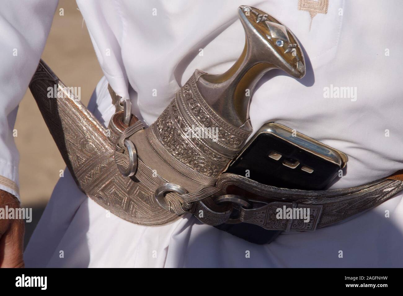 Ein OMANISCHES Gent trägt eine zeremonielle Khanjar Dolch und einem Mobiltelefon. Stockfoto