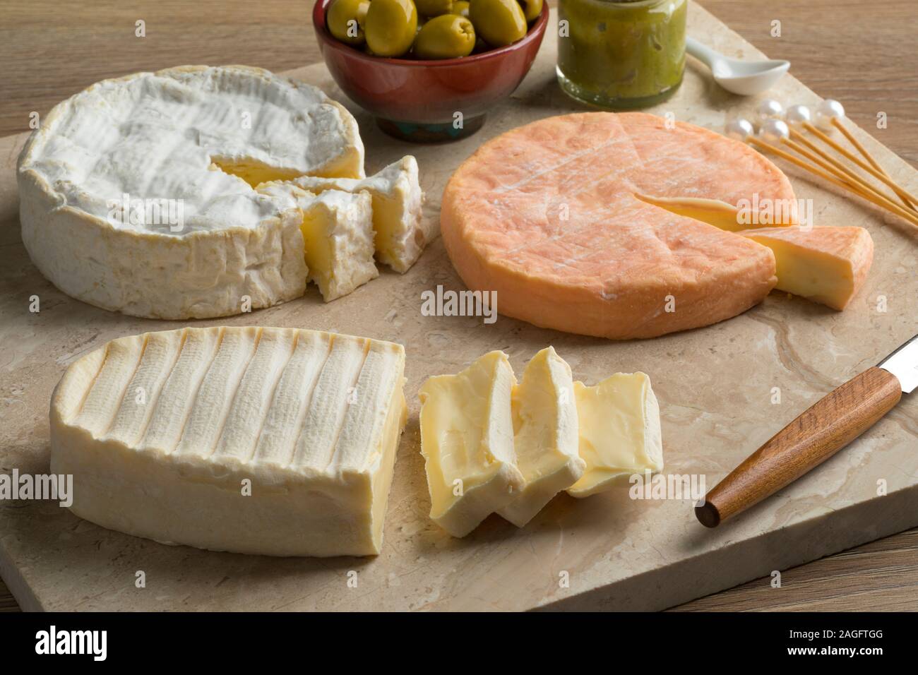 Vielfalt der traditionellen Französischen Käsesorten wie Camembert, Munster und Le Coq de Bruyere auf einem Schneidebrett Stockfoto