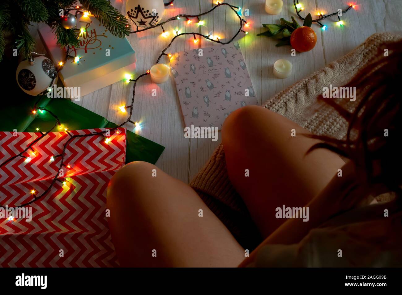 Neues Jahr Konzept, einem Mädchen, das in der Nähe der Weihnachtsbaum, eine leuchtende Girlande, Kerzen und Geschenke. Ansicht von oben für Silvester oder Weihnachten Banner. Stockfoto
