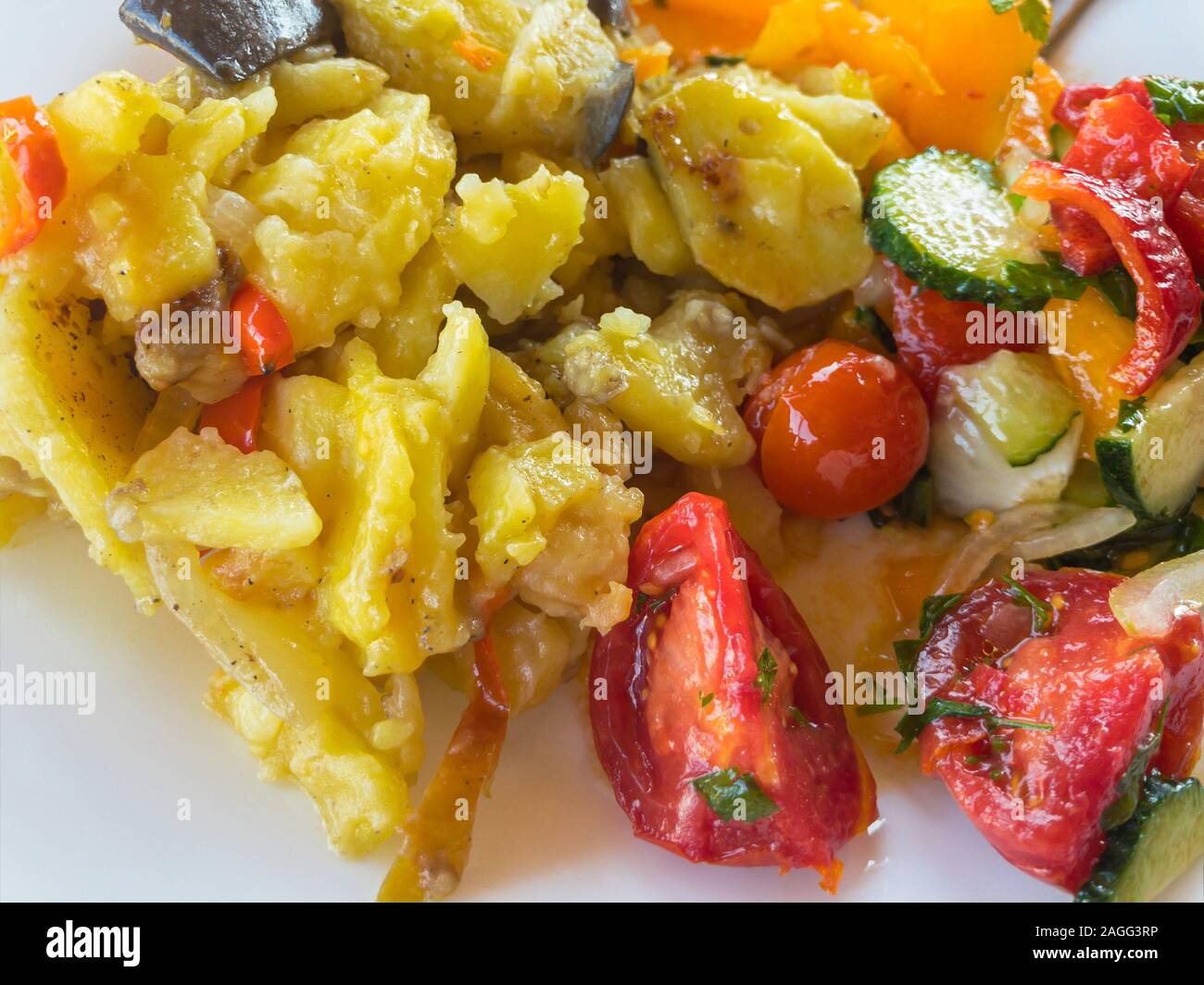 Ansicht von oben auf die Platte voller geschmorte Kartoffeln und Gemüse Salat (Tomaten, Gurken, Zwiebel) Stockfoto