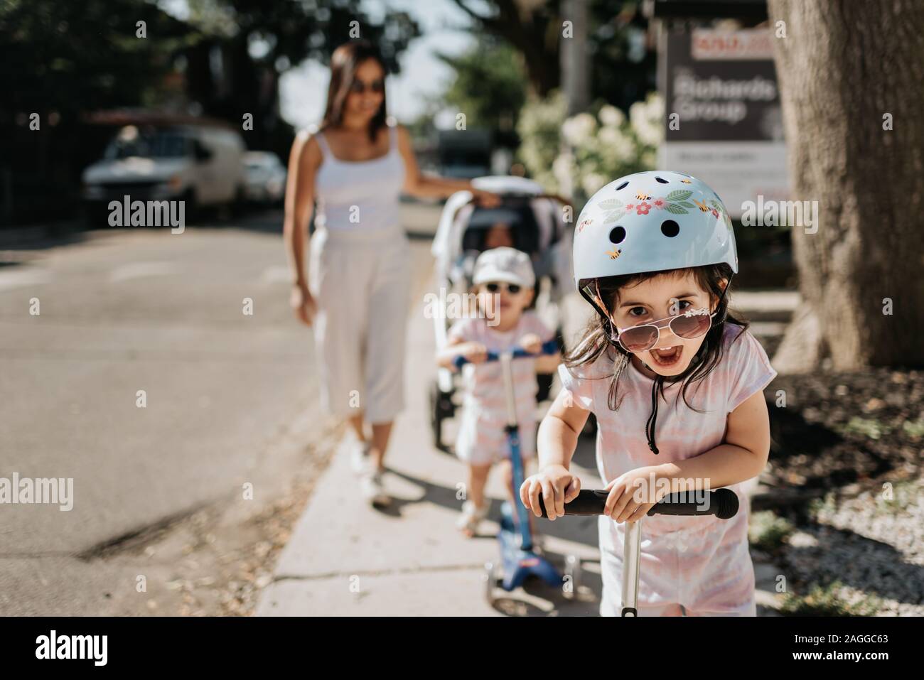 Mutter und Töchter spielen push Roller in der Nachbarschaft Stockfoto