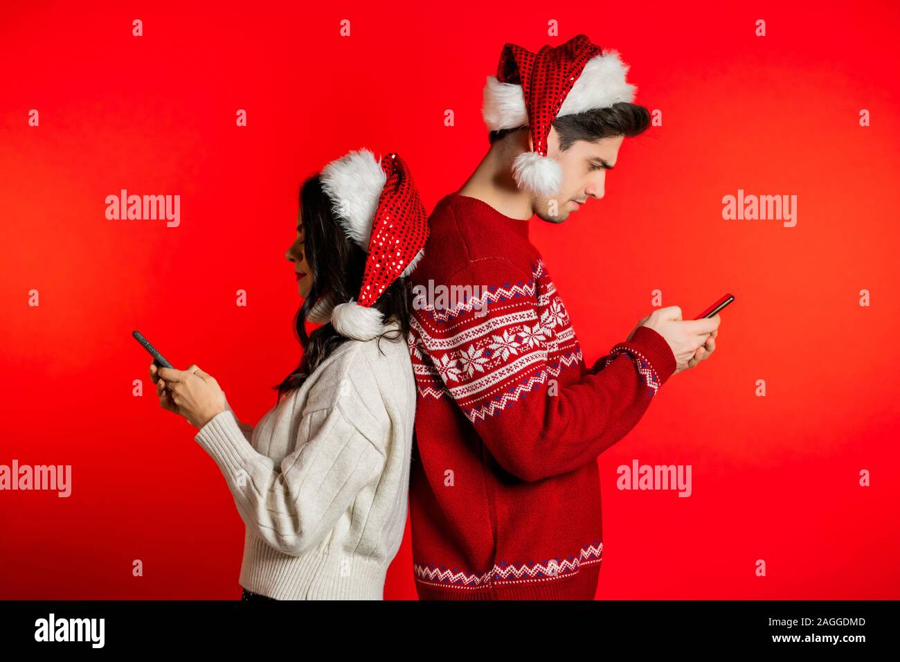 Junges Paar in Santa Hüte stehen den Rücken und Drucken von Nachrichten Stockfoto