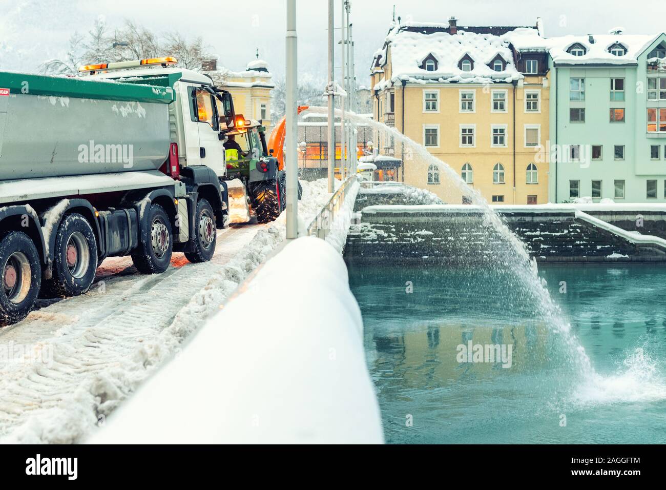 Schwere kommunale Dienstleistungen Maschinen Schnee entfernen aus den Straßen der Stadt. Großer Traktor Schneegebläse bläst den Schnee von Bridge Road in Fluss. Reinigung Straßen Stockfoto