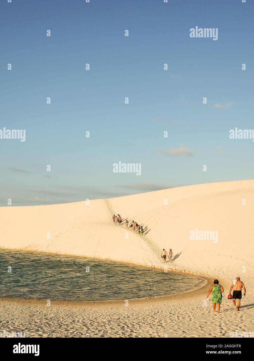Touristen zu Fuß durch die heiße Sonne und Sand Dünen der Lençóis Maranhenses Nationalpark - Barreirinhas, Maranhão, Brasilien. Stockfoto