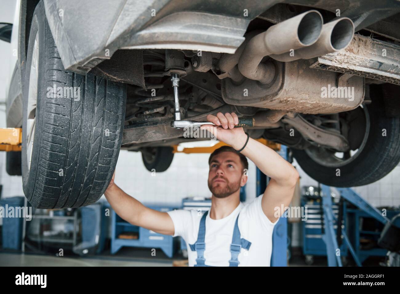 Stoßdämpfer auf das Foto. Mitarbeiter in der blauen Uniform arbeitet im Automobil Salon Stockfoto