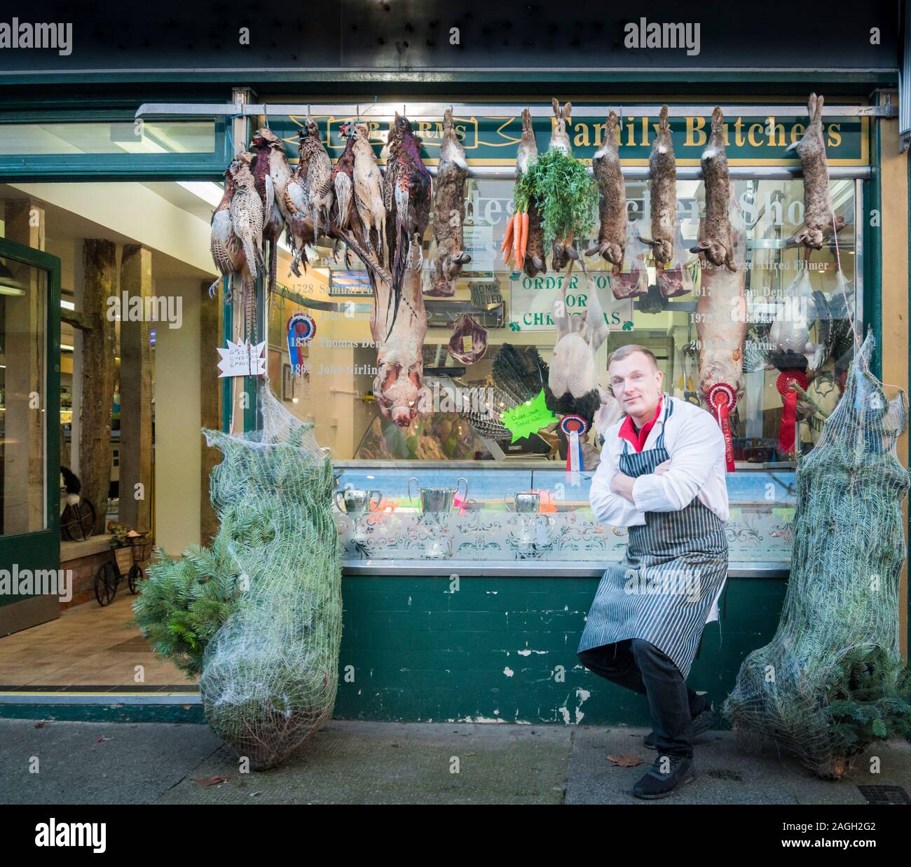 Ein männlicher Metzger, außerhalb seiner Schaufenster mit Fasanen und Hasen auflegen für die Anzeige Stockfoto