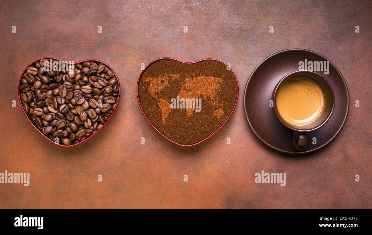 Eine Tasse cremigen Espresso, gemahlenen Kaffee und gerösteten Bohnen in eine Herzförmige Schale mit einer Karte der Welt Stockfoto