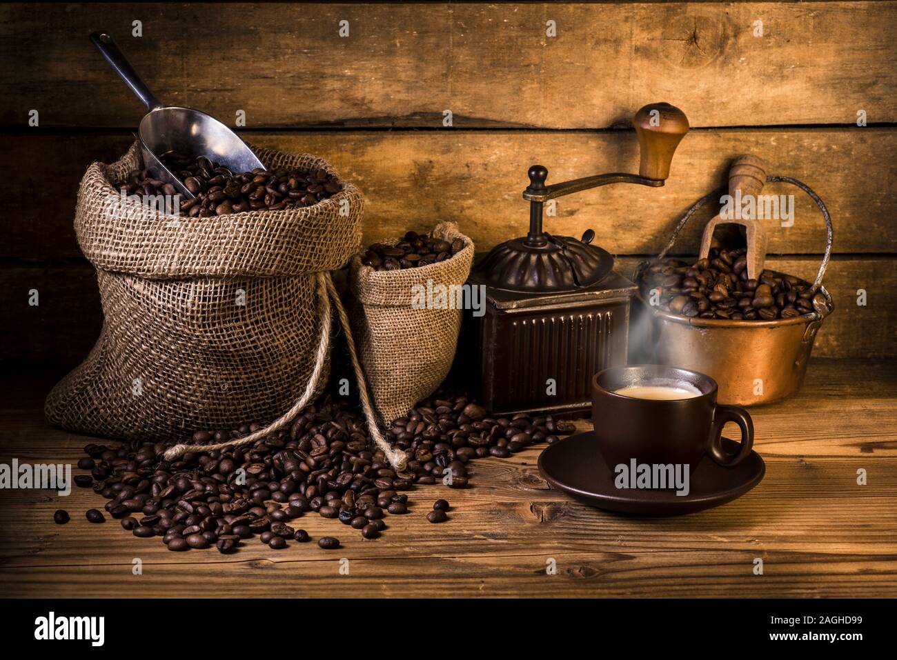 Kaffeebohnen in Jute Sack mit Holz Grinder und einer Tasse Kaffee Stockfoto
