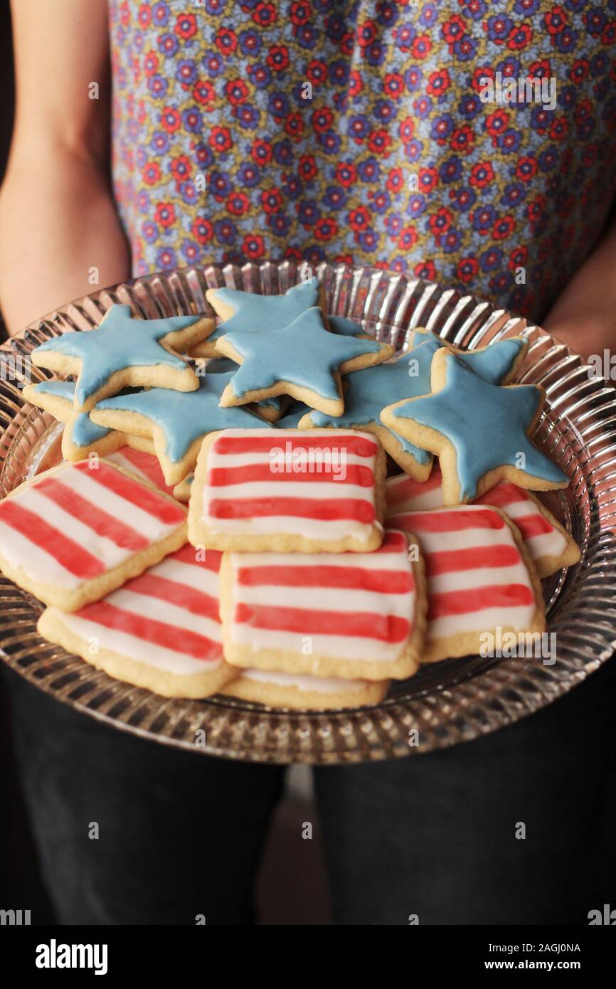Frau mit einem Teller voll mit patriotischen Cookies, dekoriert wie Sterne und Streifen Stockfoto