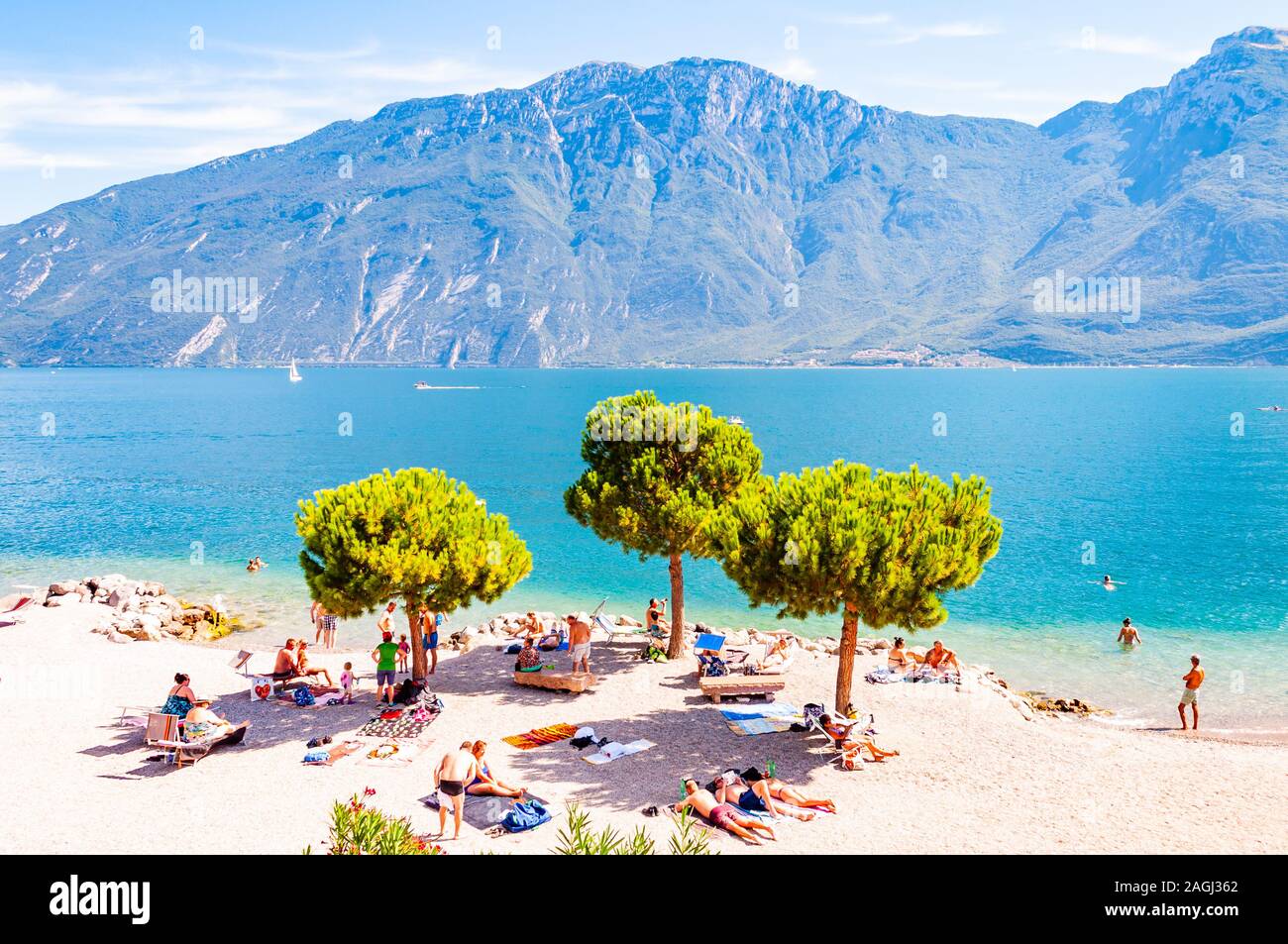 In Limone am Gardasee, Lombardei, Italien - 12 September 2019: Cosy Beach auf der westlichen Küste des Sees. Menschen schwimmen Sonnen am Ufer unter hohem Ev Stockfoto