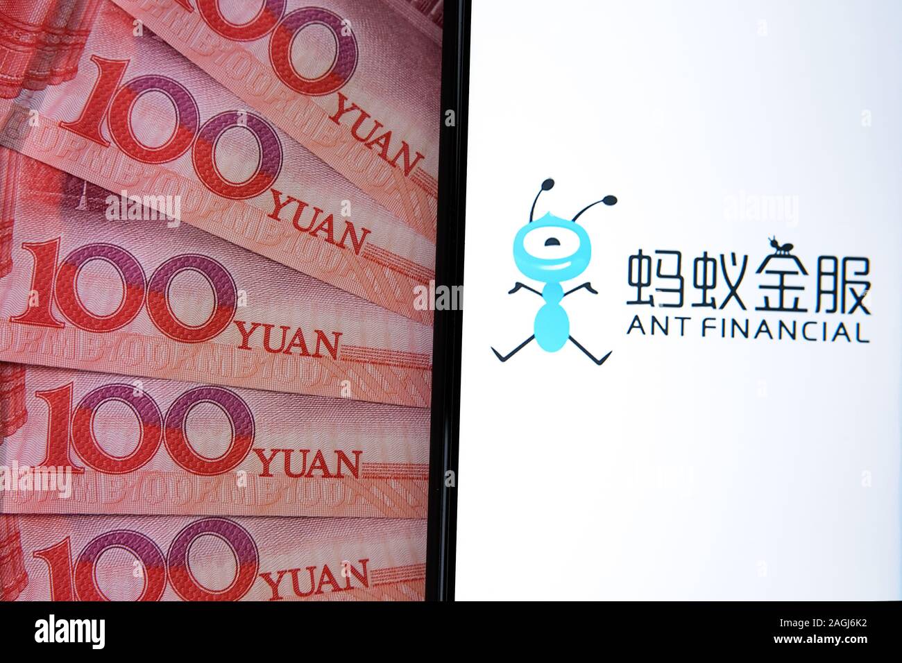 Ant finanzielle Logo auf dem Bildschirm des Smartphones neben Chinesisch 100 Yuan Banknoten. Konzeptionelle Foto. Stockfoto