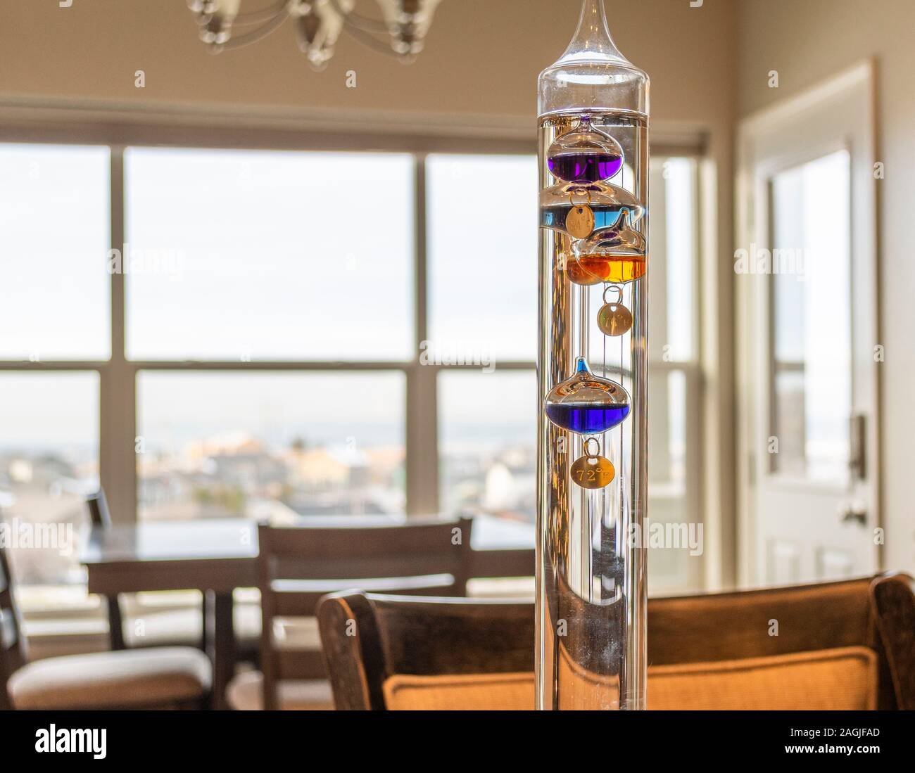Eine bunte, Glas, Flüssigkeit gefüllt Galileo Thermometer misst die Innentemperatur in einem Zimmer mit Aussicht. Stockfoto