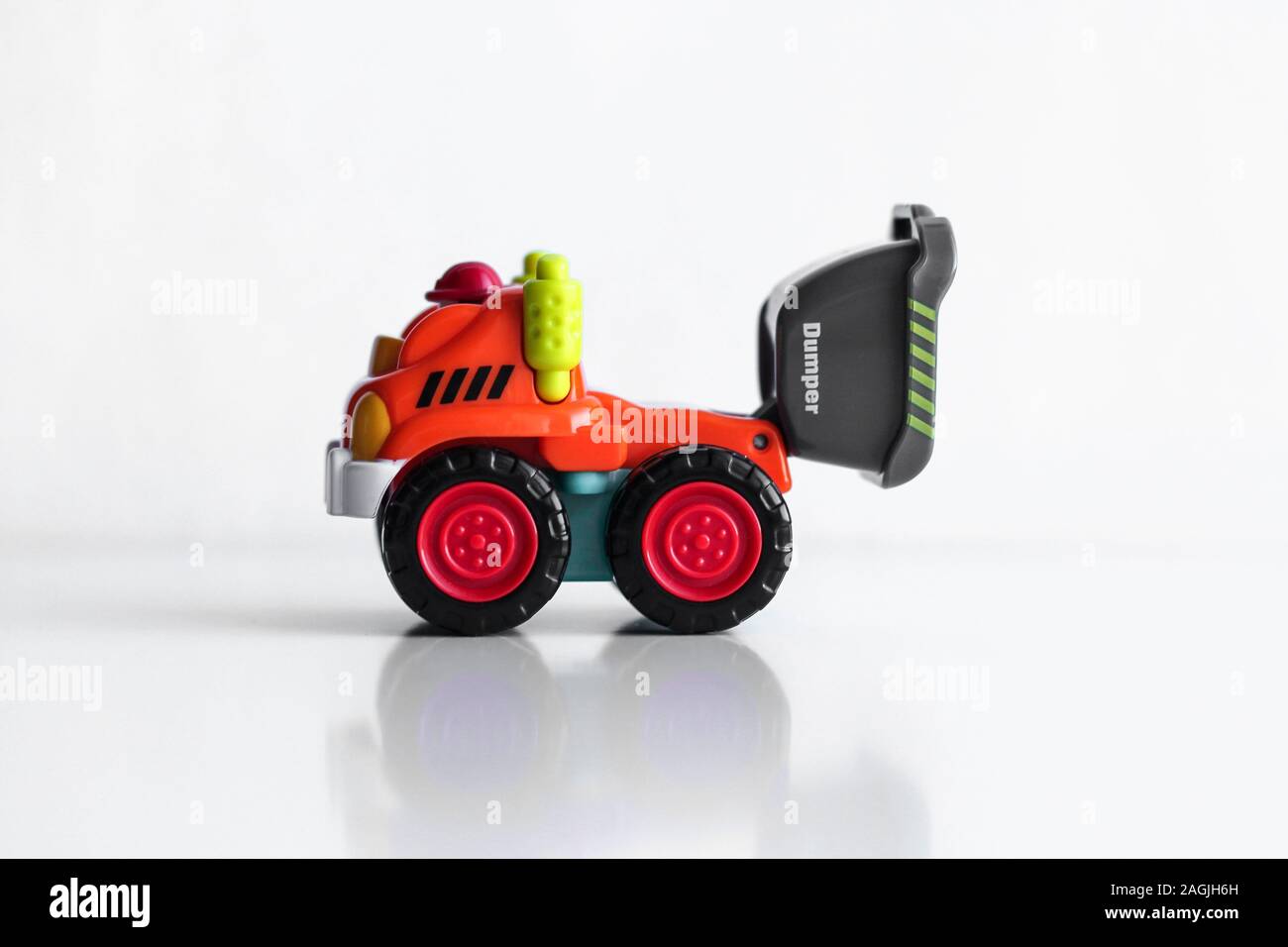 Kunststoff Dump Truck Spielzeug Bau fahrzeug auf weißem Hintergrund mit  Reflexion isoliert. Dumper Seite anzeigen. Orange Fahrzeug mit roten Räder  und Name Text. Operator in roten Schutzhelm Stockfotografie - Alamy