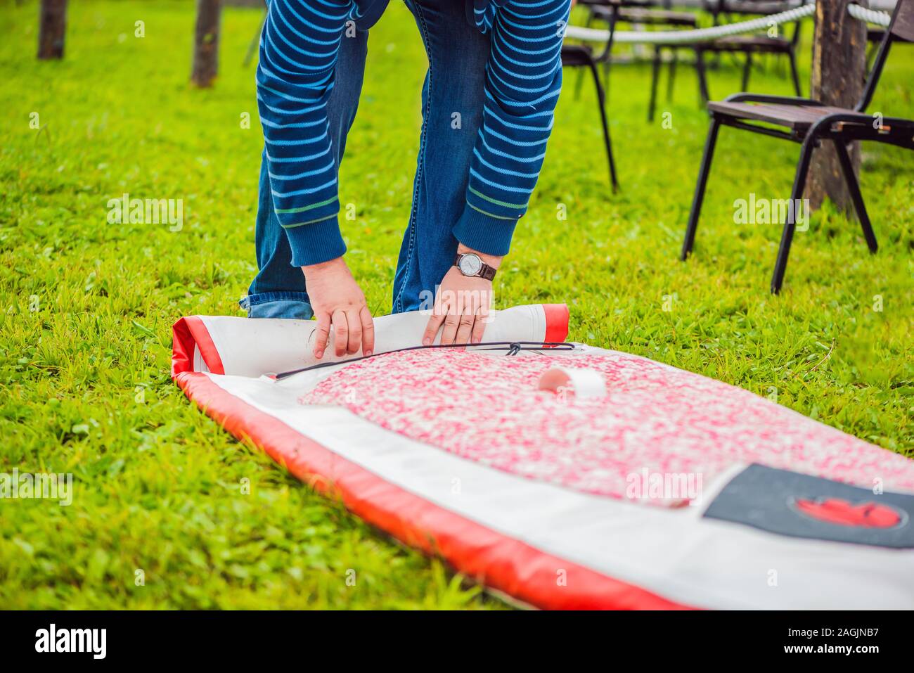 Ein Mann bläst und kollabiert SUP ein Mann bläst und kollabiert SUP. Freizeit und Sport im Freien Konzept Stockfoto