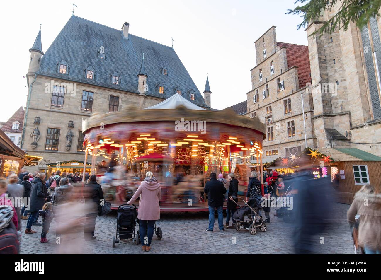 19 Dezember 2019, Niedersachsen, Osnabrück: A Merry-go-round bewegt sich auf dem Weihnachtsmarkt vor dem historischen Rathaus (Hintergrund, l). Foto: Friso Gentsch/dpa Stockfoto