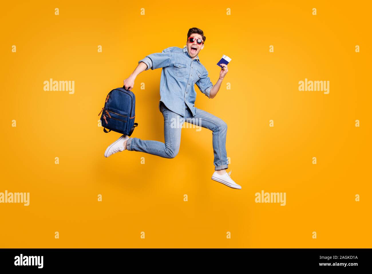 Volle Länge Körper Größe gedreht Foto von schreienden Mann laufen Springen in Richtung Flughafen in weiße Schuhe und Tasche in der Hand isoliert leuchtend gelben Farbe Stockfoto