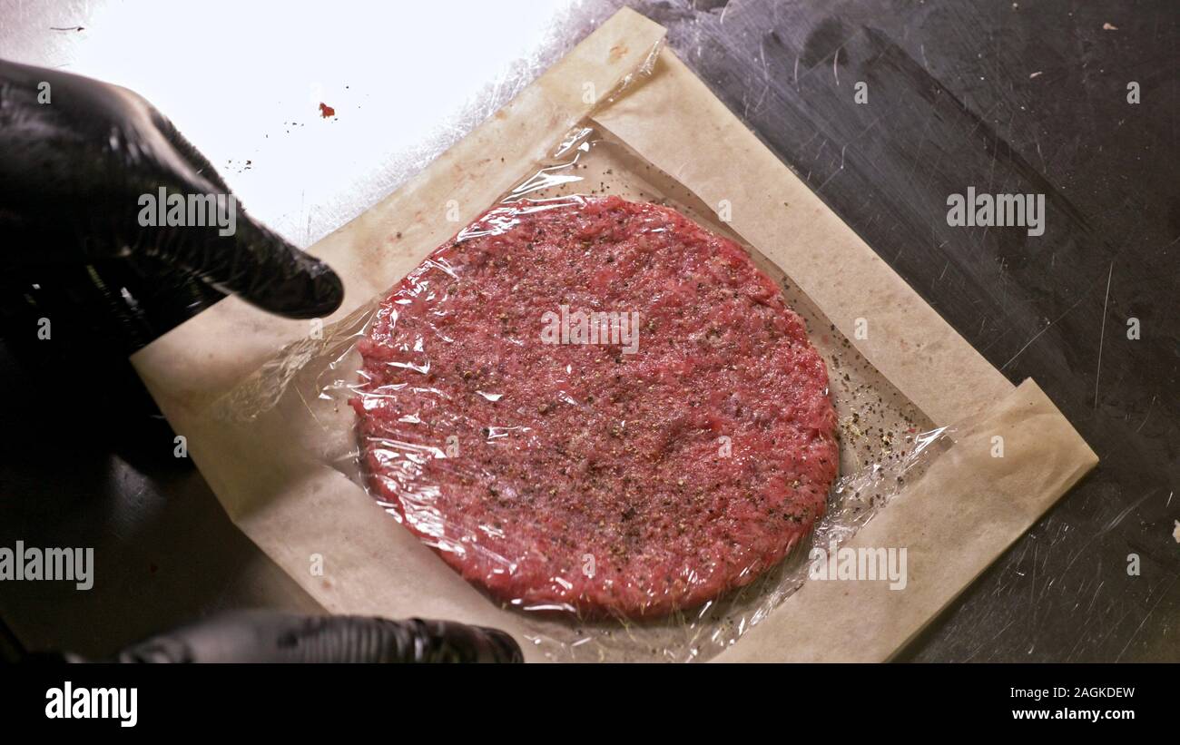 Kochen macht Fleisch Medaillons für Burger. Koch in schwarz Handschuhe macht Schnitzel essen. Die koteletts sind in Stahl Ring in eine noch Medaillon eingeebnet. Stockfoto
