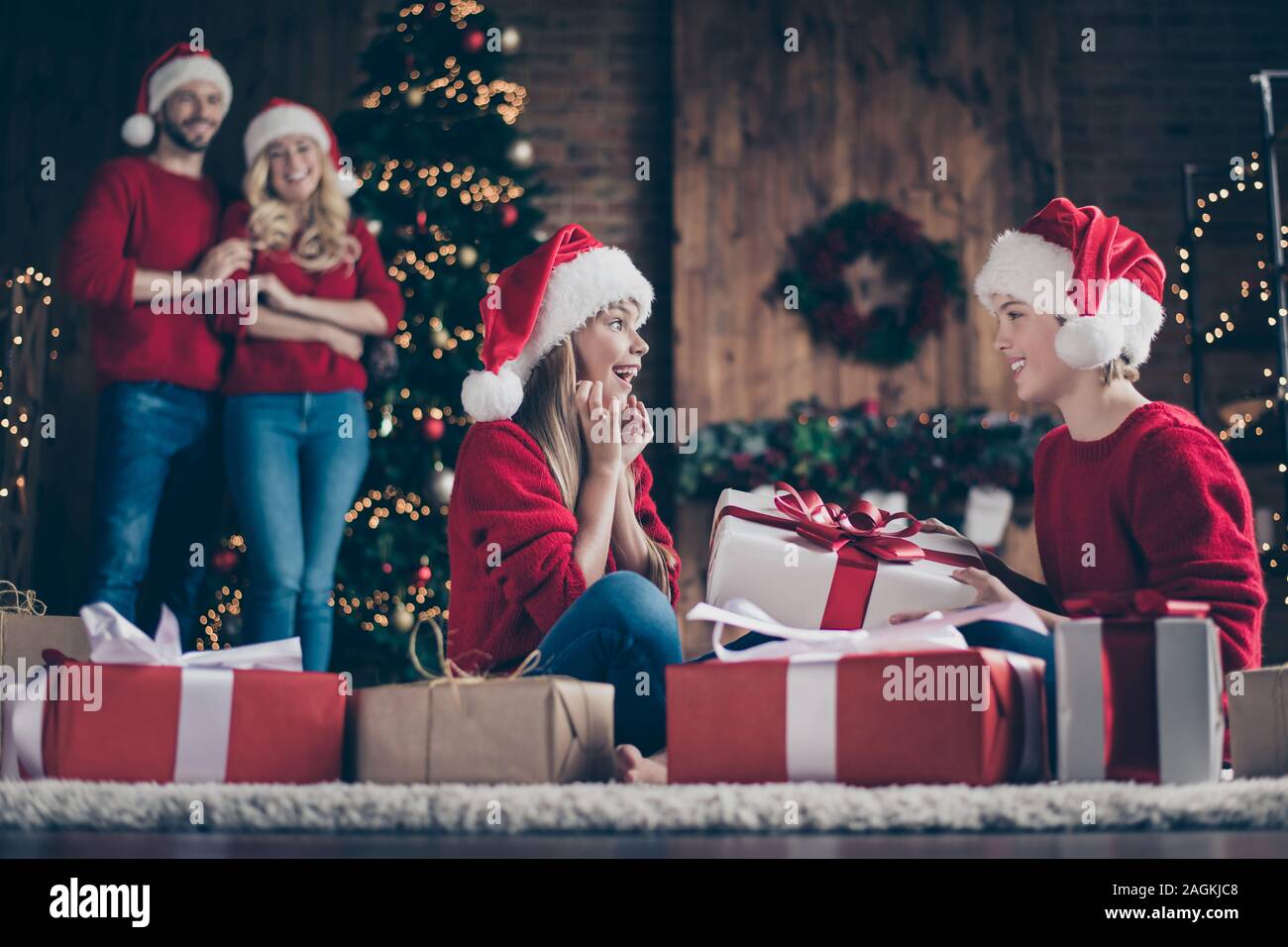 Profil Foto der vollständigen Familie Eltern zwei Kinder den Austausch von x-mas Geschenke sitzen gemütlich eingerichtet, in der Nähe von Garland Licht Neujahr Baum tragen Stockfoto