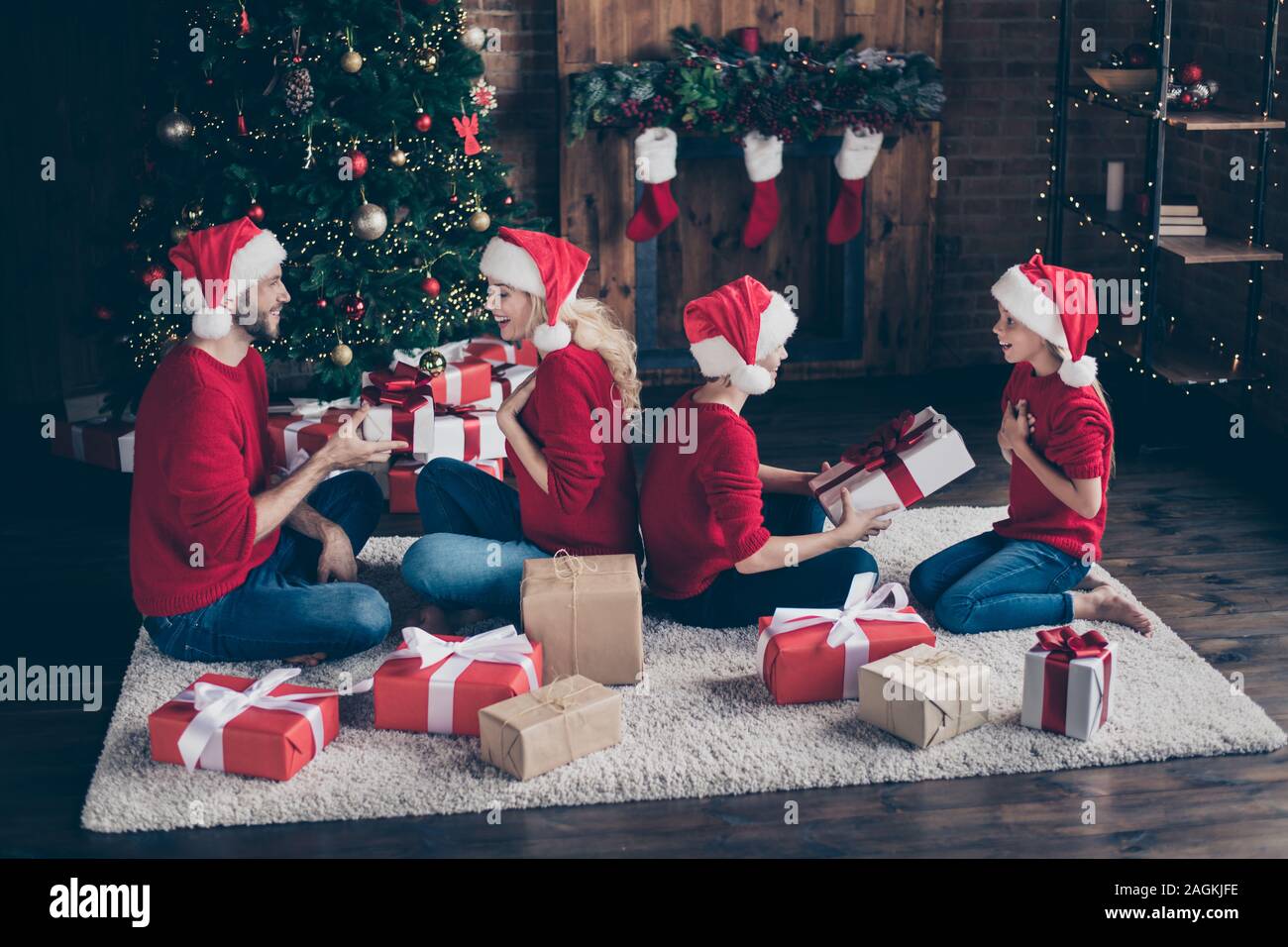 Profil Foto von großen Familie Papa Mama zwei Kinder den Austausch von x-mas Geschenke sitzen gemütlich eingerichtet, in der Nähe von Garland Licht Neujahr Baum drinnen tragen Stockfoto