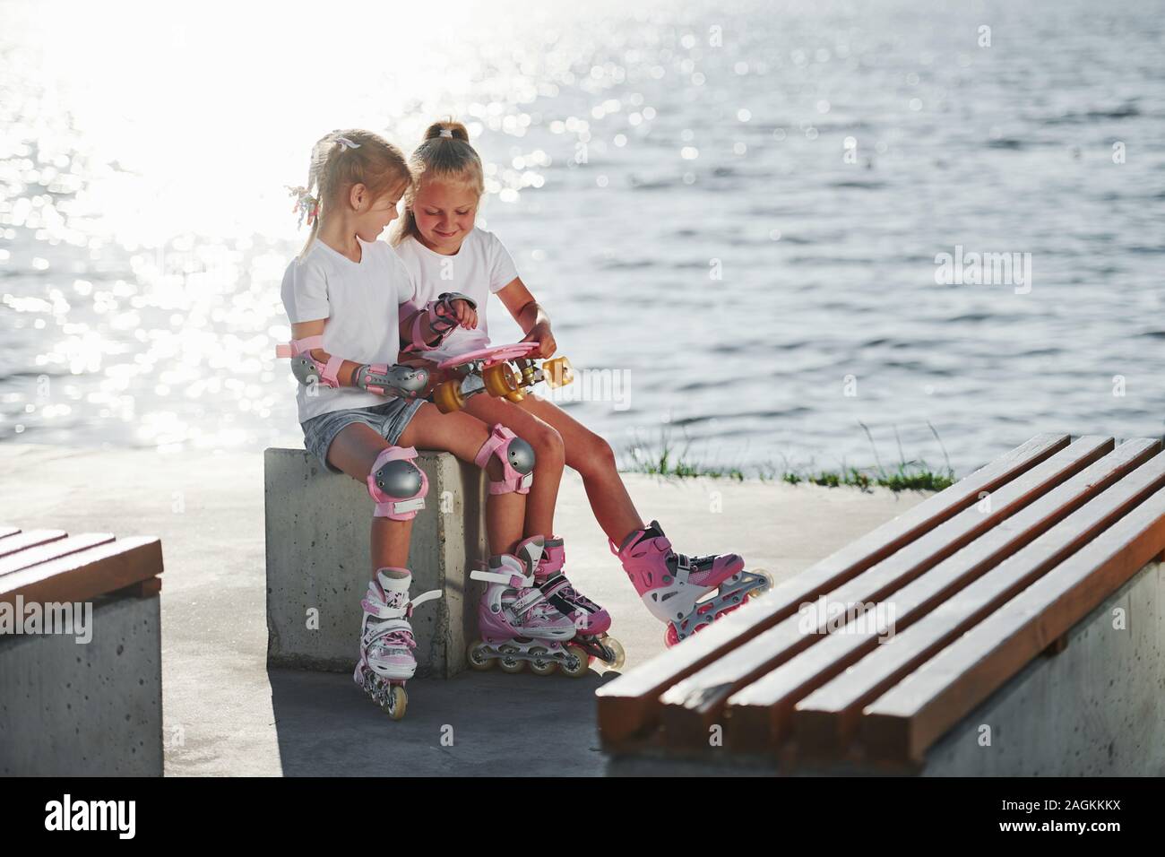 Zwei kleine Mädchen mit Rollschuhen im Freien in der Nähe der See im Hintergrund Stockfoto