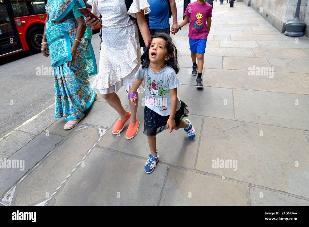 London, England, UK. Junge Mädchen zu Fuß, widerstrebend, mit ihrer Familie Stockfoto