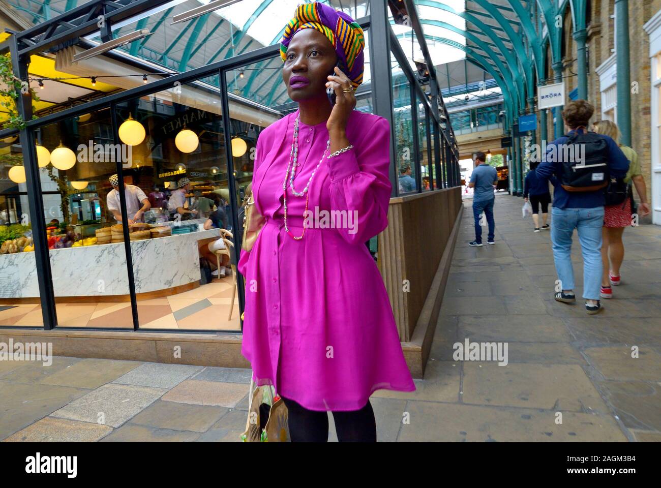 London, England, UK. Afrikanische Frau in sehr bunte Kleidung auf Ihr Mobiltelefon, Covent Garden Stockfoto