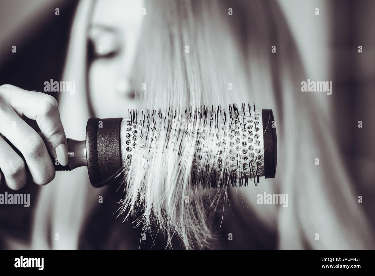 Kamm runde Haarbürste lange Haare, im Hintergrund das verschwommene Gesicht eines Mädchens, bw Foto. Stockfoto