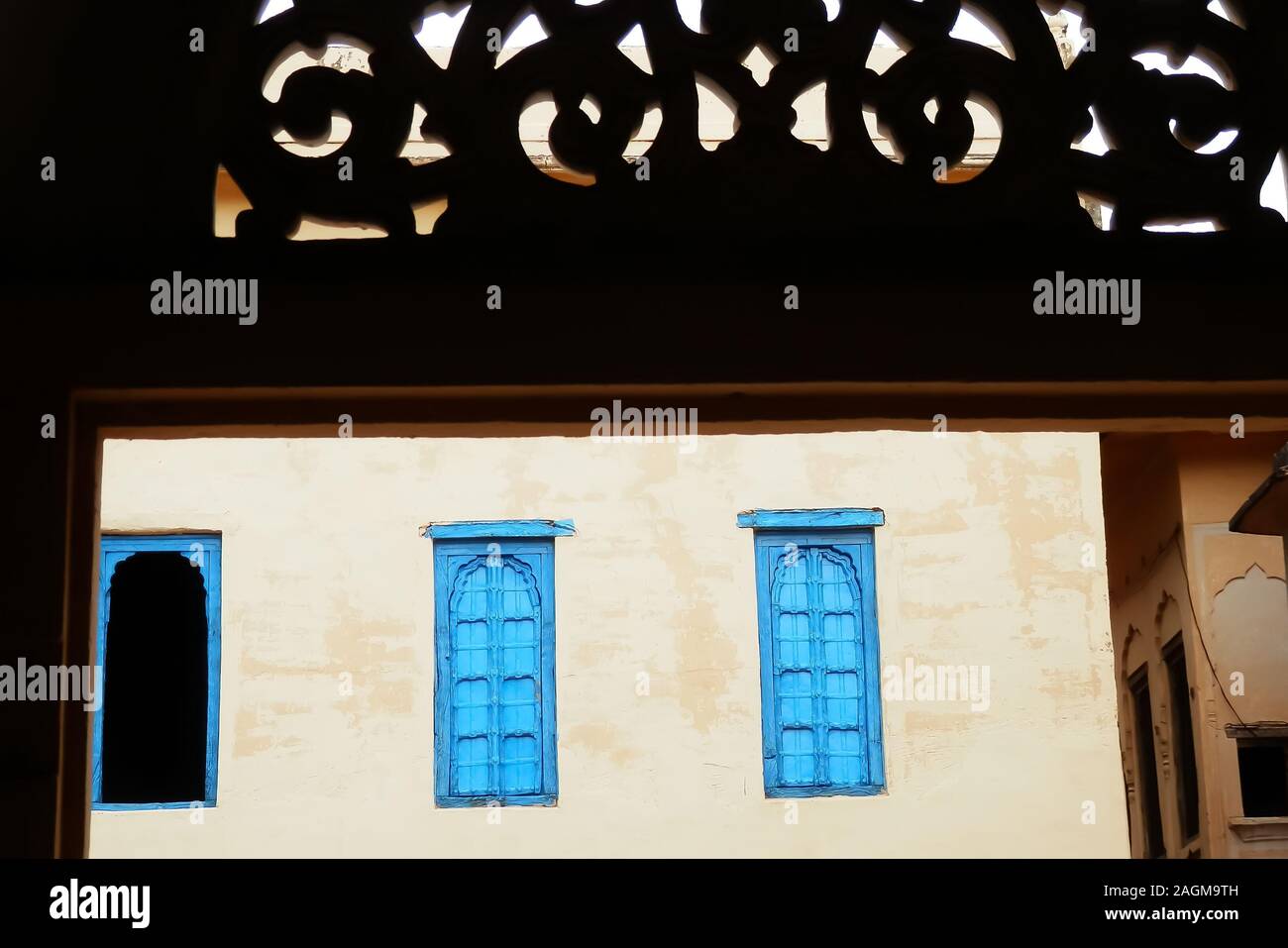 Bunte blue windows durch ein Fenster mit ornamentalen Schnitzereien gesehen, in einem Dorf in der Wüste Thar, Rajasthan, Nordindien. Stockfoto