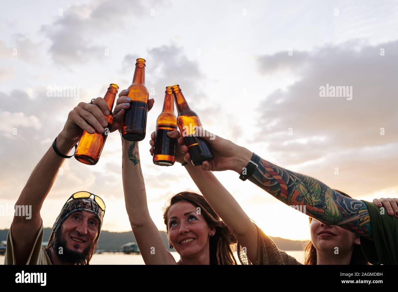 Fröhliche Freunde Toasten und Bierflaschen klirren, wenn Party am Strand Stockfoto