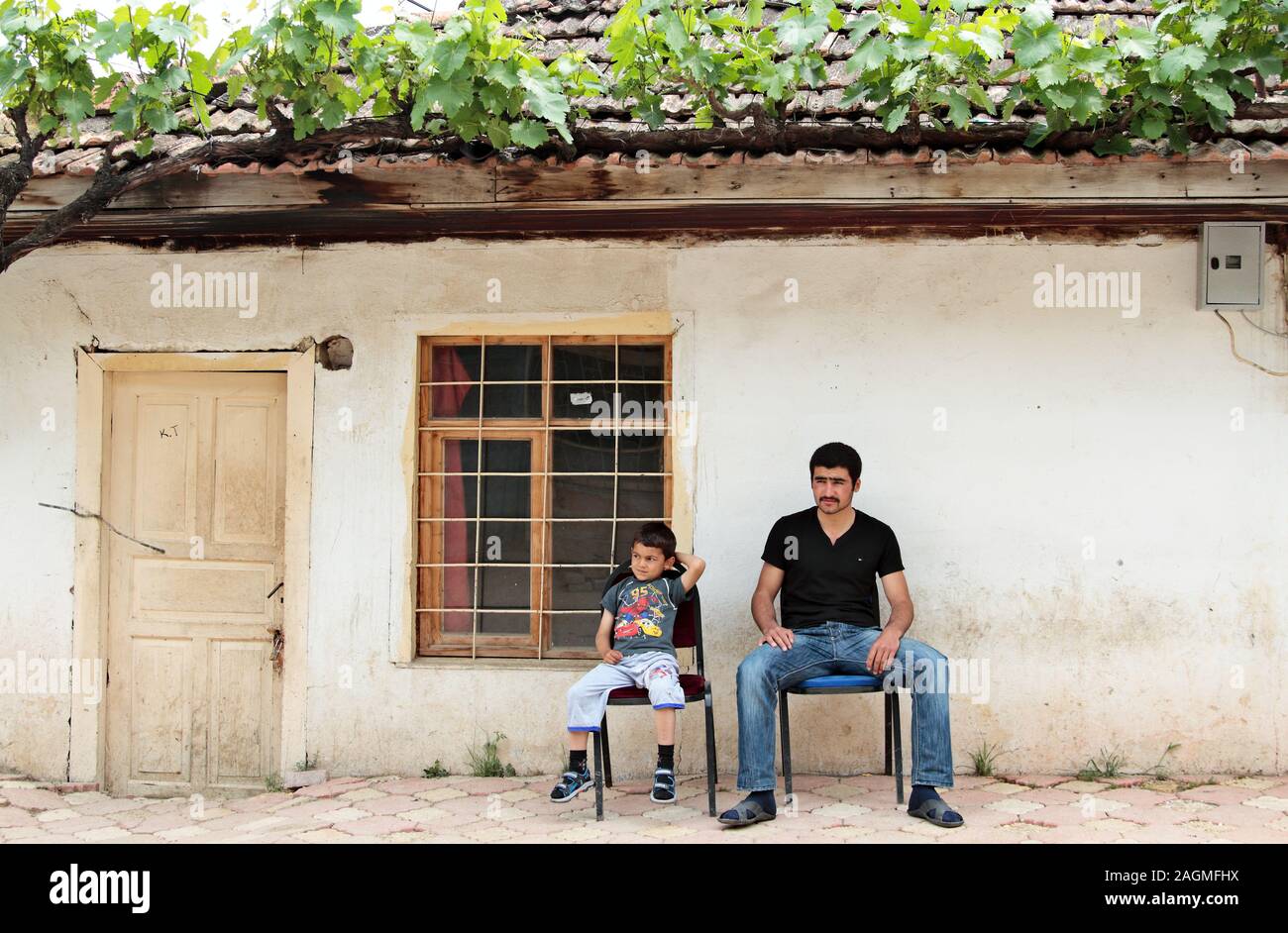 Ein Mann und sein Sohn vor ihrem Haus sitzen in der Straße an der Ausländer Stockfoto