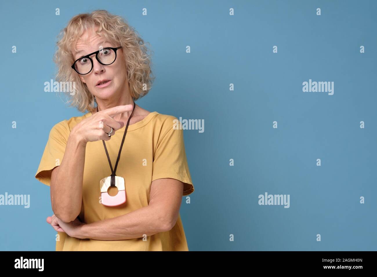 Gerne reife Frau in Gläsern und gelb Shirt, Finger weg Stockfoto